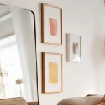 Idées déco mur : miroir vertical et cadres sur mur blanc lumineux